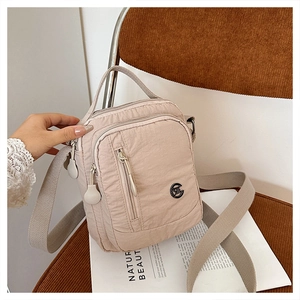 Detail of beige waterproof nylon crossbody bag with adjustable strap and multi-pocket design