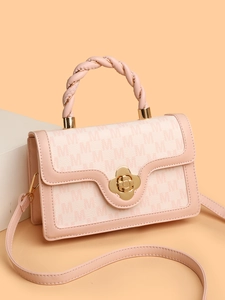 Detail view of pink monogram crossbody bag with braided handle and gold floral clasp