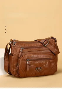 Vue détaillée du sac à bandoulière en cuir marron avec trois fermetures éclair et boucle cœur