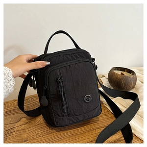Close-up of black nylon crossbody bag with multiple zippers and adjustable shoulder strap