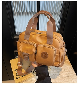 Close-up of camel nylon crossbody bag with dual zipper pockets and top handles