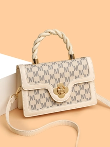Macro view of cream crossbody bag with M-pattern print and woven leather handle details