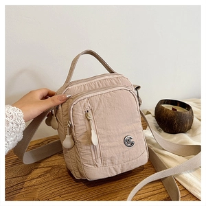 Detail of waterproof nylon crossbody bag with multi-zipper compartments and metal logo