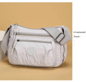 Detail of light gray nylon crossbody bag with multiple zipper pockets and smooth texture