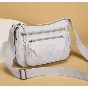 Close-up of light gray multi-pocket nylon shoulder bag with wide adjustable strap