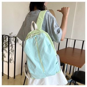 Outdoor model shot of waterproof yoga backpack in light blue and green patchwork fabric