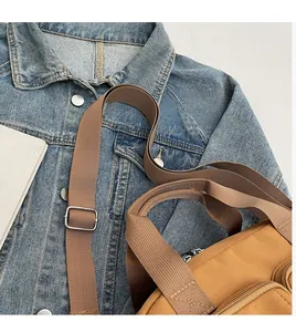 Detail of adjustable thick woven strap and metal buckle on earthy canvas crossbody bag