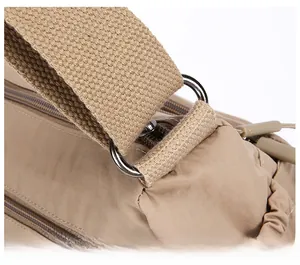 Close-up of durable metal D-ring and reinforced stitching on khaki nylon bag strap