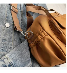 Detail of brown nylon shoulder bag with adjustable strap and silver metal hardware accents