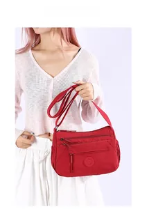 Detailed view of red multi-pocket oxford cloth crossbody bag with adjustable strap