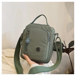 Detail of sage green nylon crossbody bag with adjustable strap and waterproof fabric