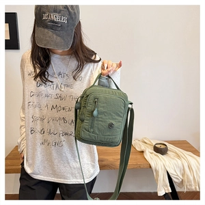 Detailed view of sage green nylon crossbody bag with adjustable strap and zip pocket