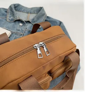 Detail of smooth two-way metal zipper and nylon fabric handle on a brown casual bag