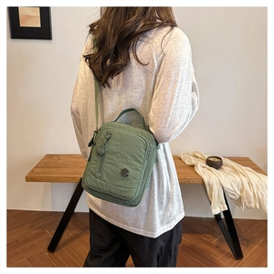 Detail of green nylon crossbody bag showing multiple zip pockets and adjustable strap
