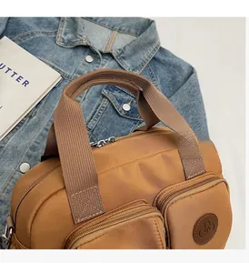 Detailed close-up of camel brown canvas handbag with multiple front zipper pockets and handle