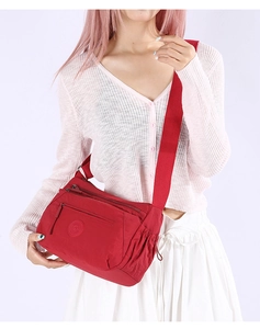 Detail of red water-resistant nylon crossbody bag with multiple zippers and wide strap
