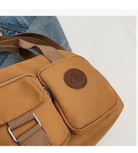 Close-up of brown nylon shoulder bag featuring functional pockets and metal hardware details