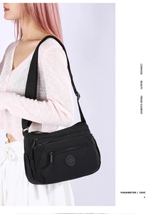 Close-up of black multi-zipper nylon crossbody bag with adjustable fabric strap