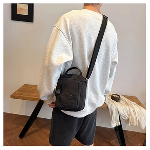 Detailed view of the waterproof nylon crossbody bag with circular logo and adjustable strap