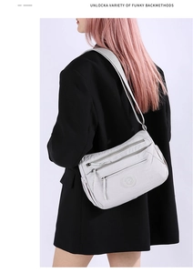 Detail of light grey multi-pocket nylon shoulder bag with adjustable strap and logo