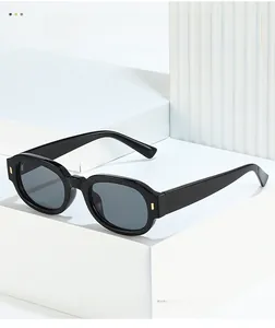 Detail of minimalist black acetate sunglasses with dark lenses and gold hinge accents
