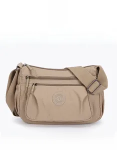 Front view of beige nylon crossbody bag with multi-zipper pockets and adjustable strap