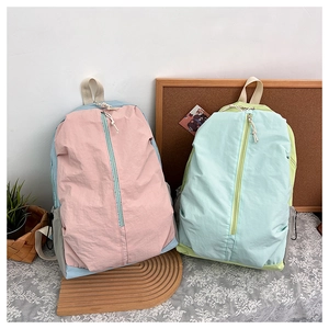 Detail of color-block nylon backpacks with vertical zippers and textured fabric finish