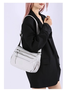 Detail view of grey multi-layer nylon crossbody bag with adjustable strap and pockets