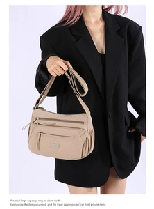 Detail of khaki oxford nylon crossbody bag with multi-layer zippers on black blazer model