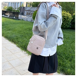 Detailed view of lightweight nylon crossbody bag with multi-layer zipper compartments
