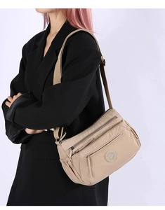 Close-up of lightweight nylon crossbody bag with multi-zipper pockets on a model