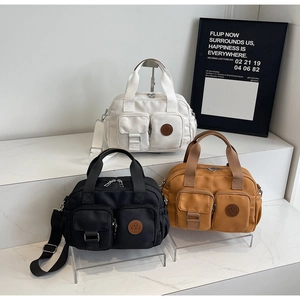 Three multi-pocket nylon Boston bags in white, black, and yellow with long straps