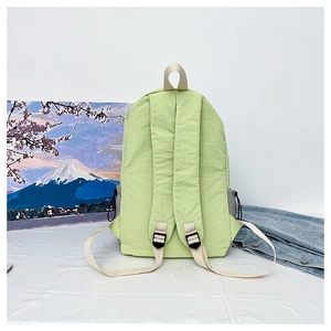Detail view of light green nylon backpack with adjustable padded straps and top handle