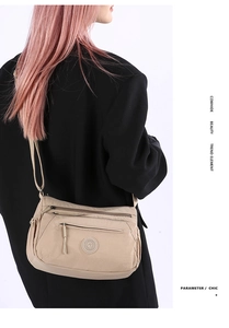 Model wearing a beige multi-pocket oxford crossbody bag with cowhide trim and zip pockets