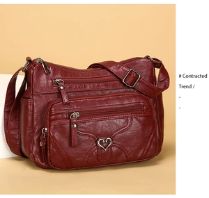 Détail du sac à bandoulière en cuir souple rouge foncé avec fermetures éclair et décorations cœur