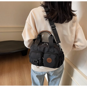 Detail of a black multi-pocket crossbody bag showing the adjustable strap and logo patch