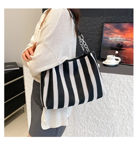 Detail of black and white striped straw tote with leather and chain shoulder strap