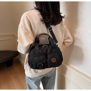 Detail of waterproof black nylon bag with adjustable wide strap and dual front pockets