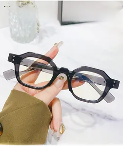 Detail view of bold hexagonal black sunglasses with silver rivet accents and glossy finish