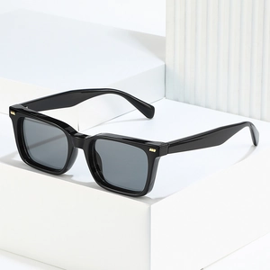 Retro square sunglasses with black frame and golden metal rivets on white minimalist blocks
