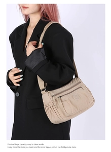 Detail view of khaki nylon crossbody bag with multi-layer zippers and durable fabric