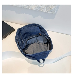 Detailed interior of the blue denim backpack featuring grey lining and metal zipper closure