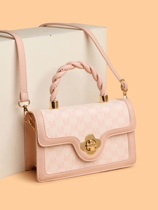Pink monogram square handbag with woven handles and gold flower clasp on white pedestal