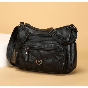 Détail du sac à bandoulière en similicuir noir avec plusieurs poches zippées et cœur
