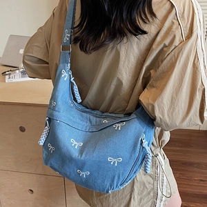 Sac hobo en denim bleu avec motifs de nœuds blancs et tirette de fermeture tressée