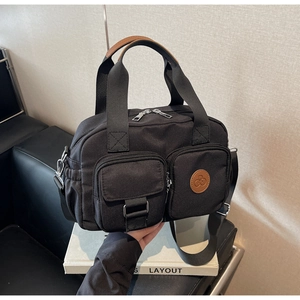 Close-up of black nylon handbag with multiple zip pockets and brown leather logo tag