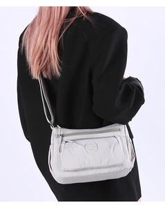 Close-up of light gray multi-layered nylon crossbody bag with adjustable strap and logo