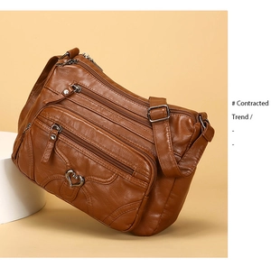 Détail du sac en cuir souple marron avec poches zippées et boucle métallique en cœur