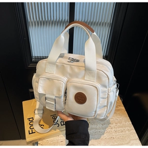 Macro view of water-resistant nylon handbag details with pockets and leather logo