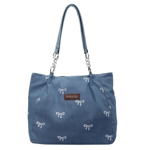 Blue denim tote bag with embroidered bow patterns and silver metal chain strap